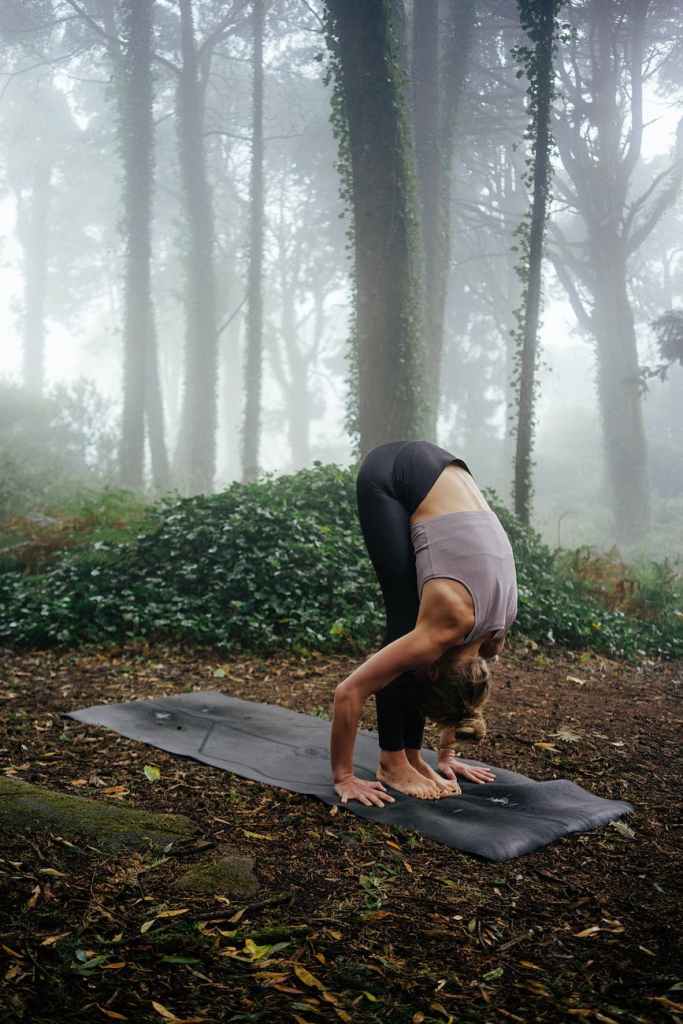 woman practicing yoga in misty forest