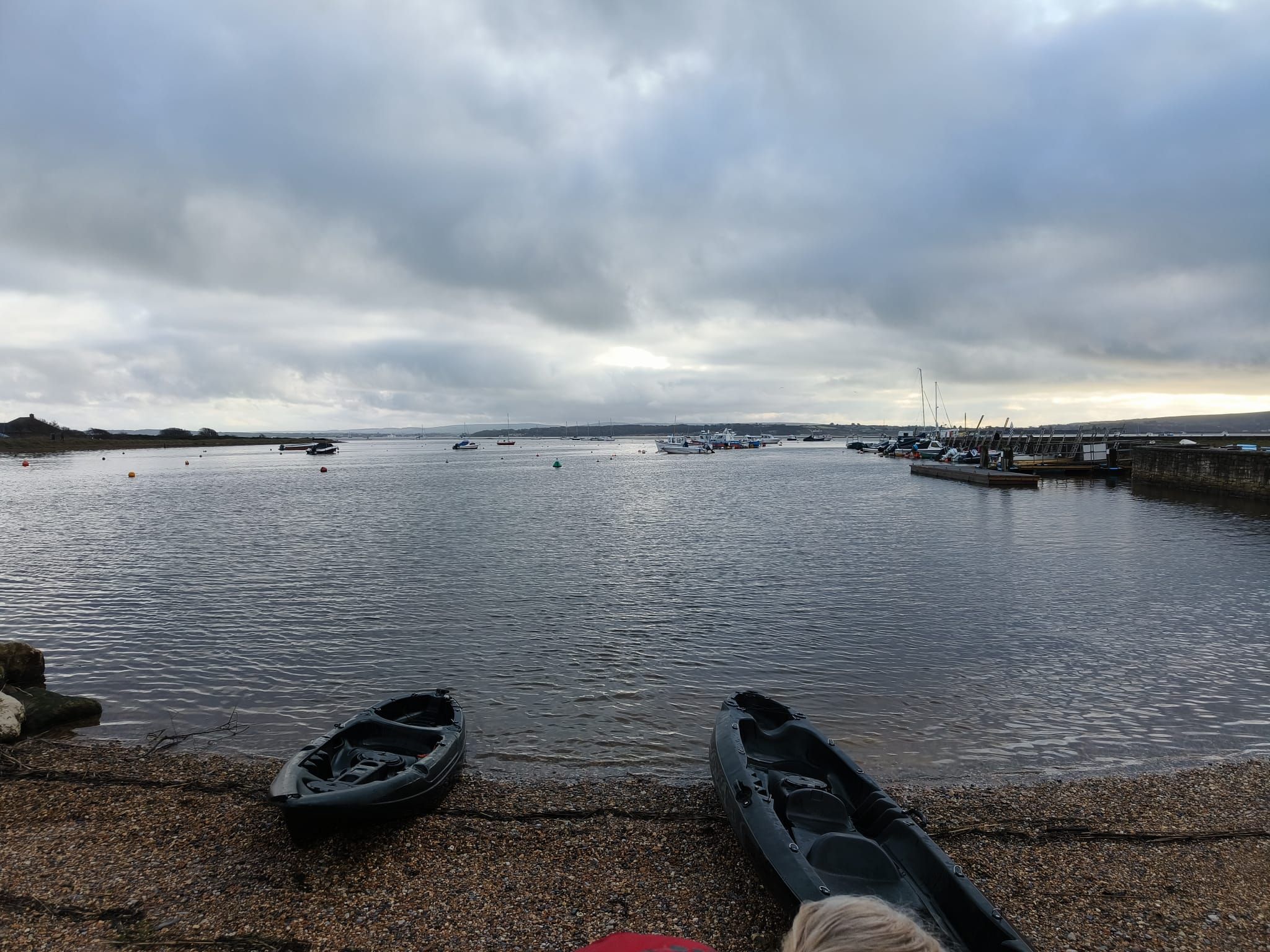 Kayaks resting beside the calm waters of the Hampshire coast at Keyhaven